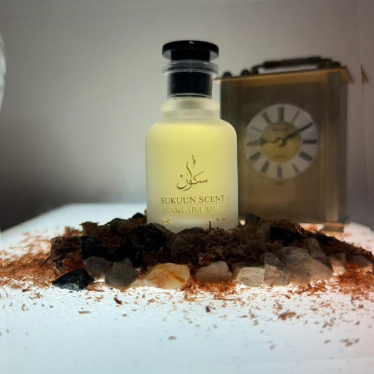 Sukuun Scent Maktab E Oud Eau de Parfum 50ML bottle surrounded by oud chips and a vintage clock.